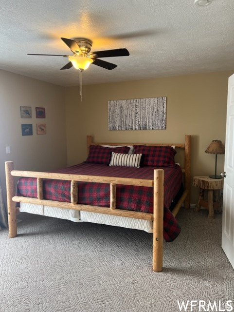 Carpeted bedroom with ceiling fan and a textured ceiling