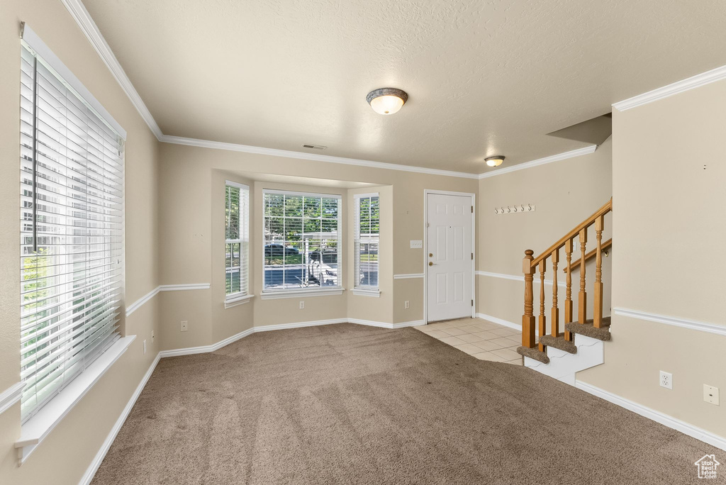 Entryway with ornamental molding and light colored carpet