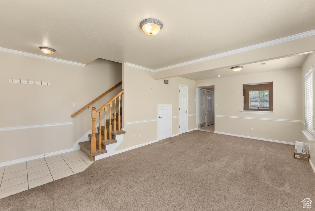 Unfurnished living room featuring carpet flooring and crown molding