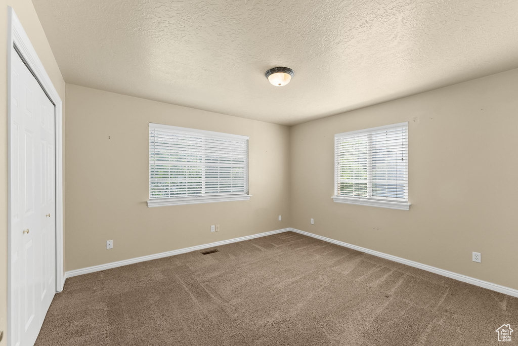 Unfurnished bedroom featuring a textured ceiling, carpet flooring, and a closet