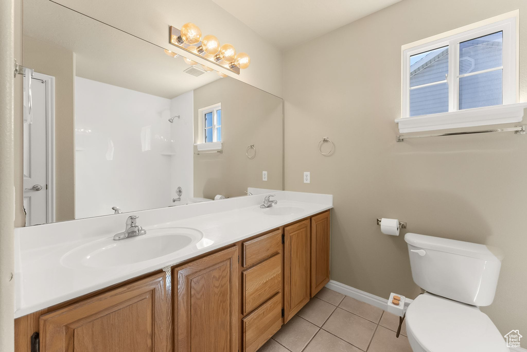 Bathroom featuring tile floors, large vanity, toilet, and double sink