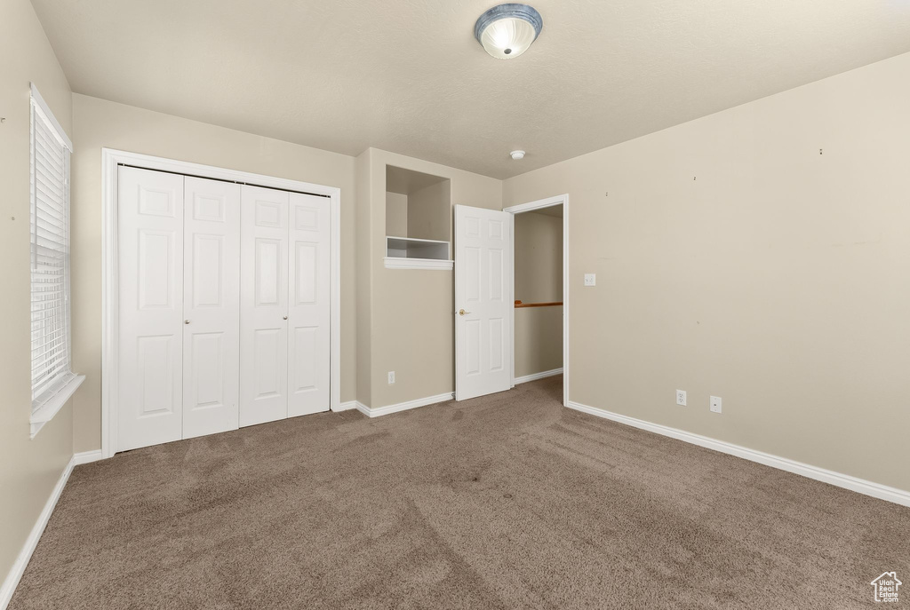 Unfurnished bedroom featuring a closet and dark carpet