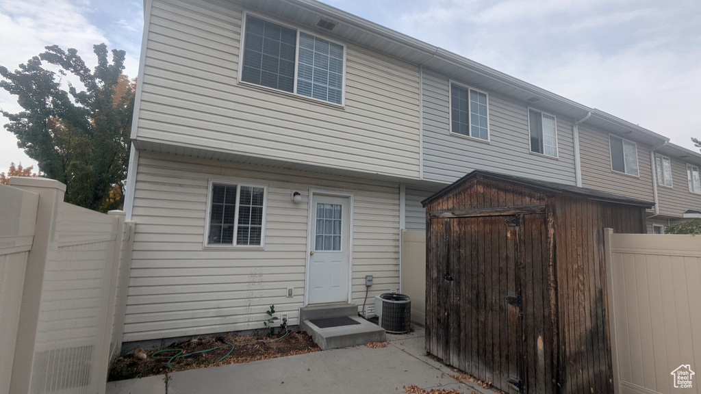 Rear view of house with a storage unit and central AC unit