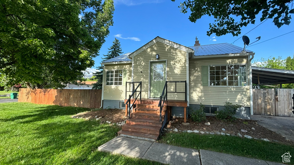 View of front of property with a front yard and a carport