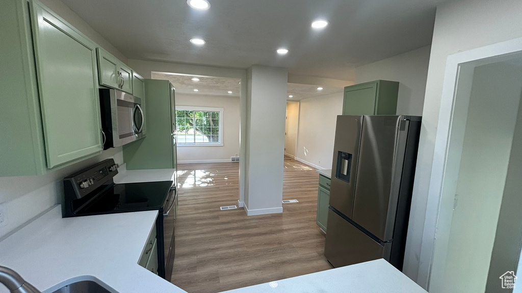 Kitchen with stainless steel appliances, green cabinetry, and dark wood-type flooring