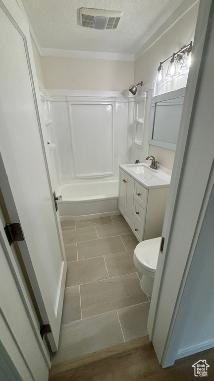 Full bathroom featuring tile flooring, bathtub / shower combination, vanity with extensive cabinet space, a textured ceiling, and toilet