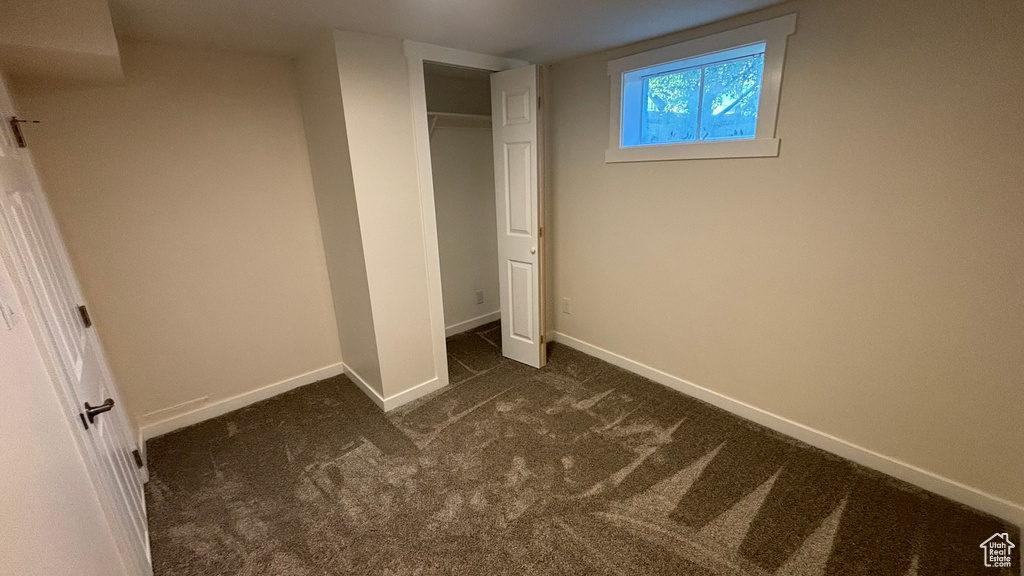 Unfurnished bedroom featuring a closet and dark colored carpet