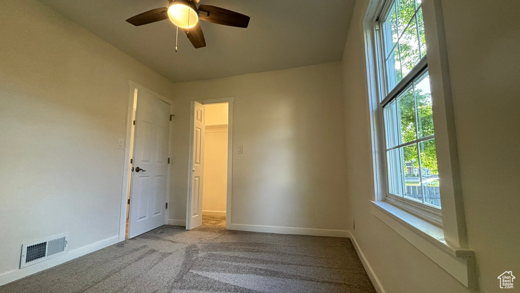 Unfurnished bedroom featuring ceiling fan, multiple windows, and carpet flooring