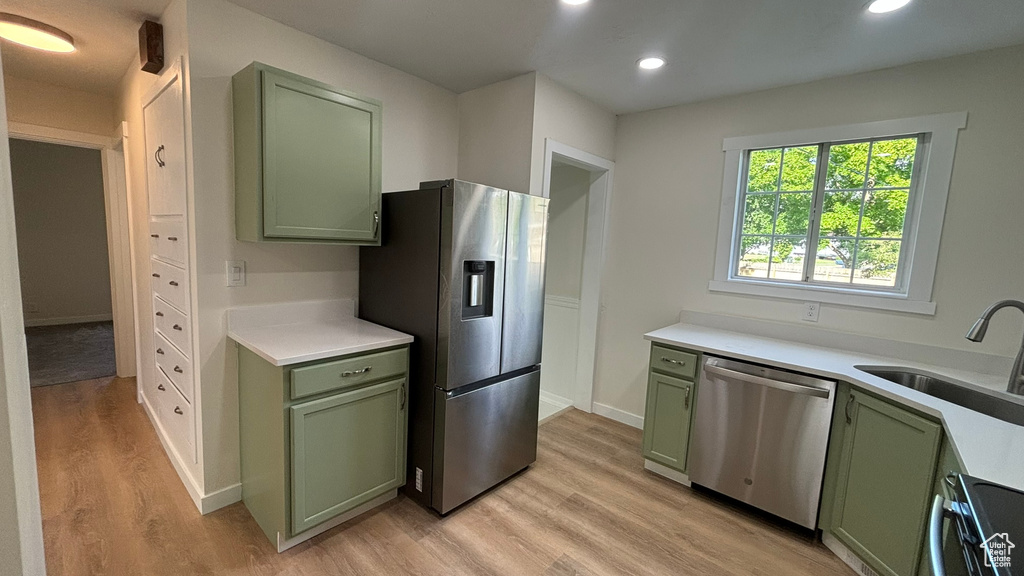 Kitchen with appliances with stainless steel finishes, sink, light hardwood / wood-style floors, and green cabinets