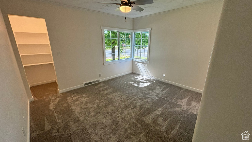 Carpeted empty room with ceiling fan and crown molding