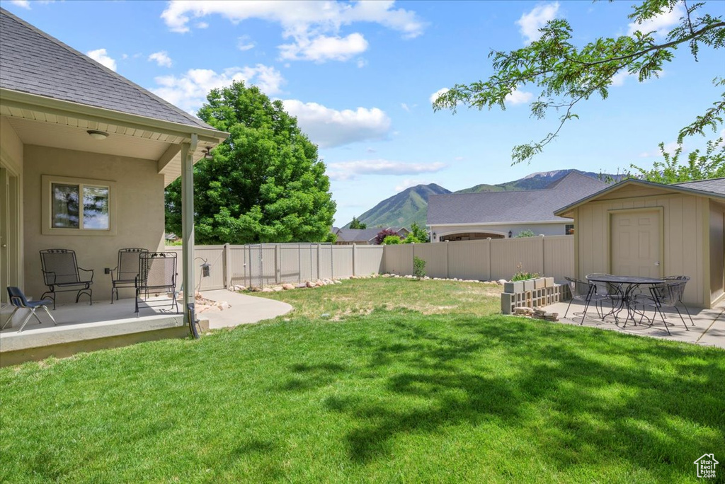 View of yard with a patio, a shed, and a mountain view