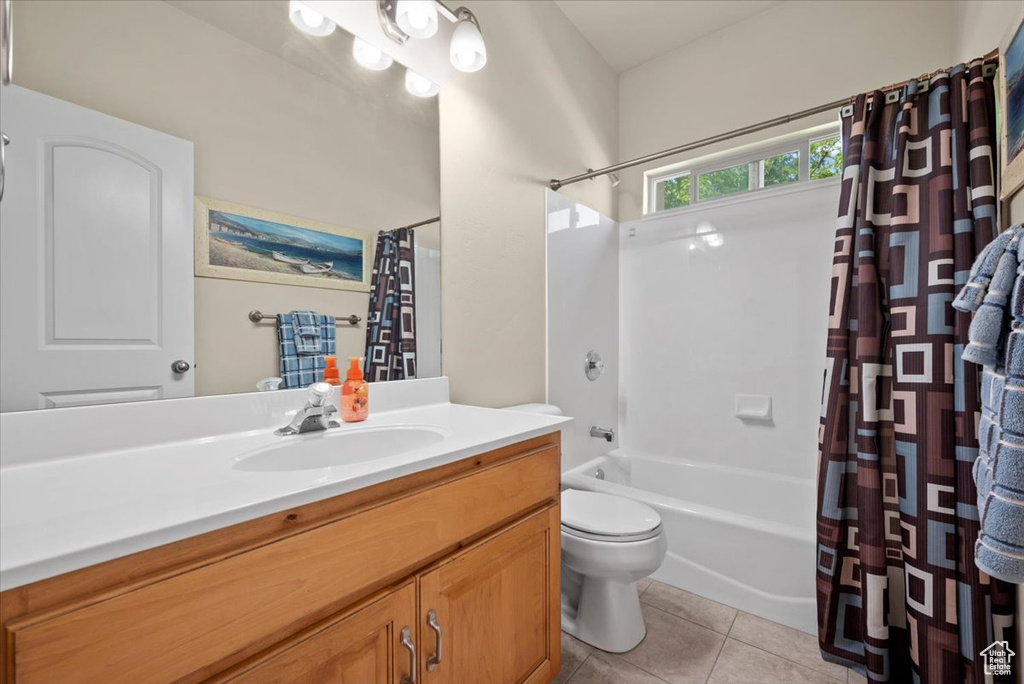 Full bathroom with tile flooring, toilet, oversized vanity, and shower / bathtub combination with curtain