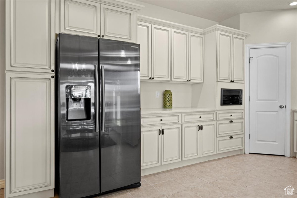 Kitchen with white cabinets, stainless steel fridge, and light tile flooring