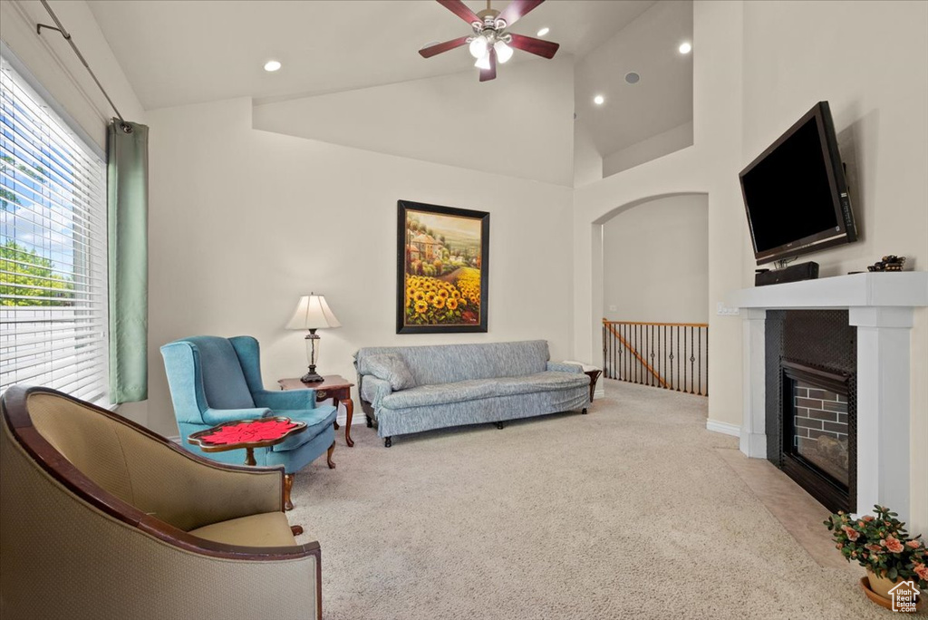 Carpeted living room with high vaulted ceiling and ceiling fan