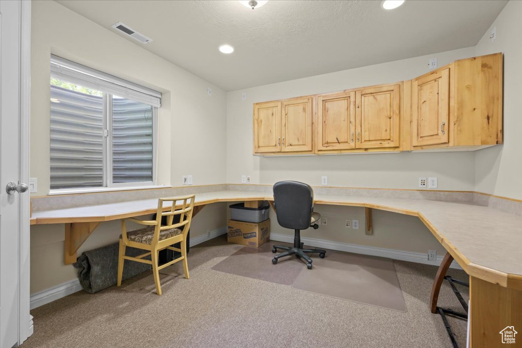 Office space with built in desk and light carpet