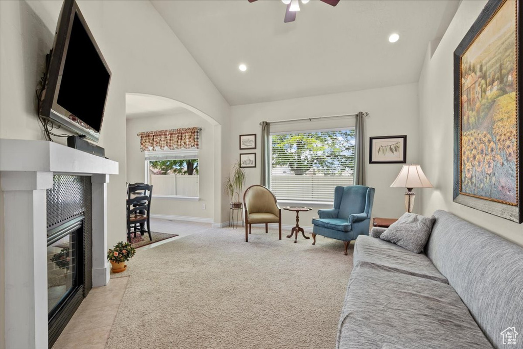 Living room featuring high vaulted ceiling, ceiling fan, and light colored carpet