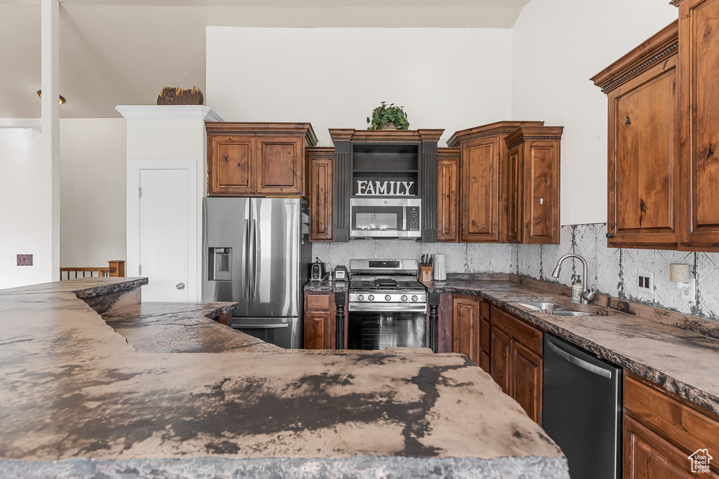 Kitchen with dark stone countertops, sink, backsplash, and appliances with stainless steel finishes