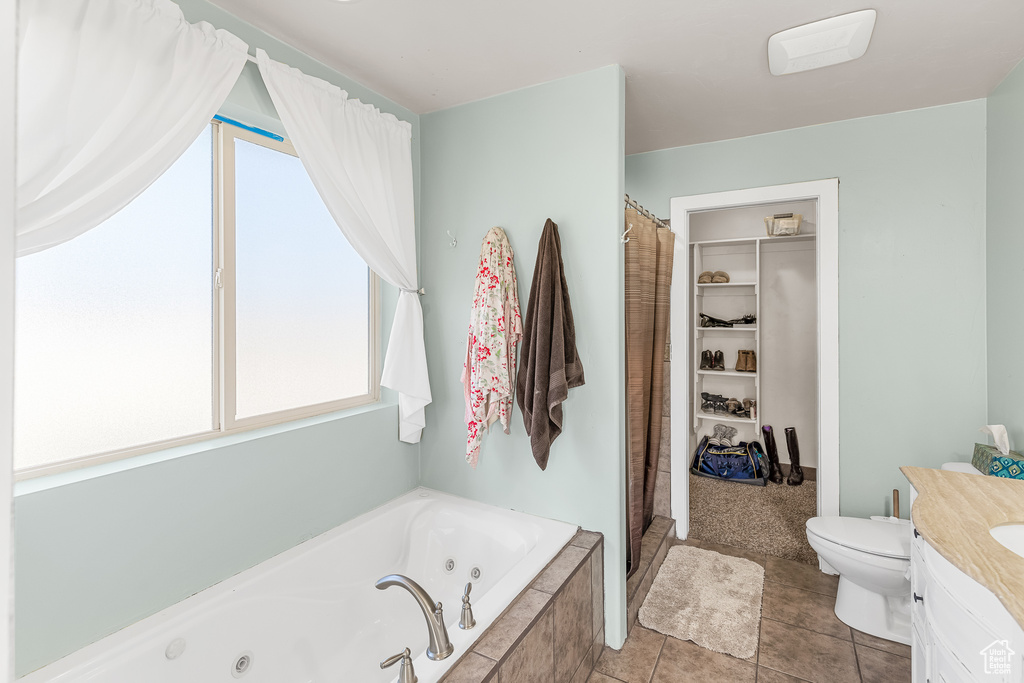 Bathroom featuring tiled bath, tile flooring, vanity, and toilet