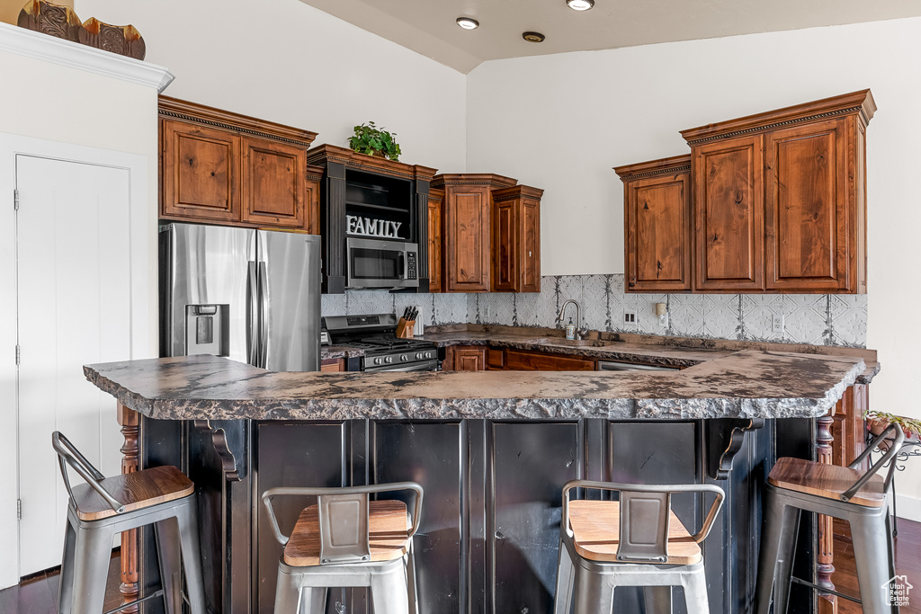 Kitchen with a breakfast bar, sink, tasteful backsplash, and stainless steel appliances