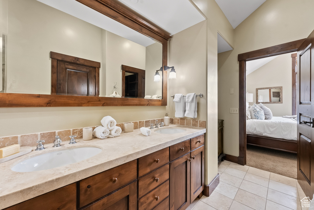 Bathroom with tile floors, lofted ceiling, double sink, and vanity with extensive cabinet space