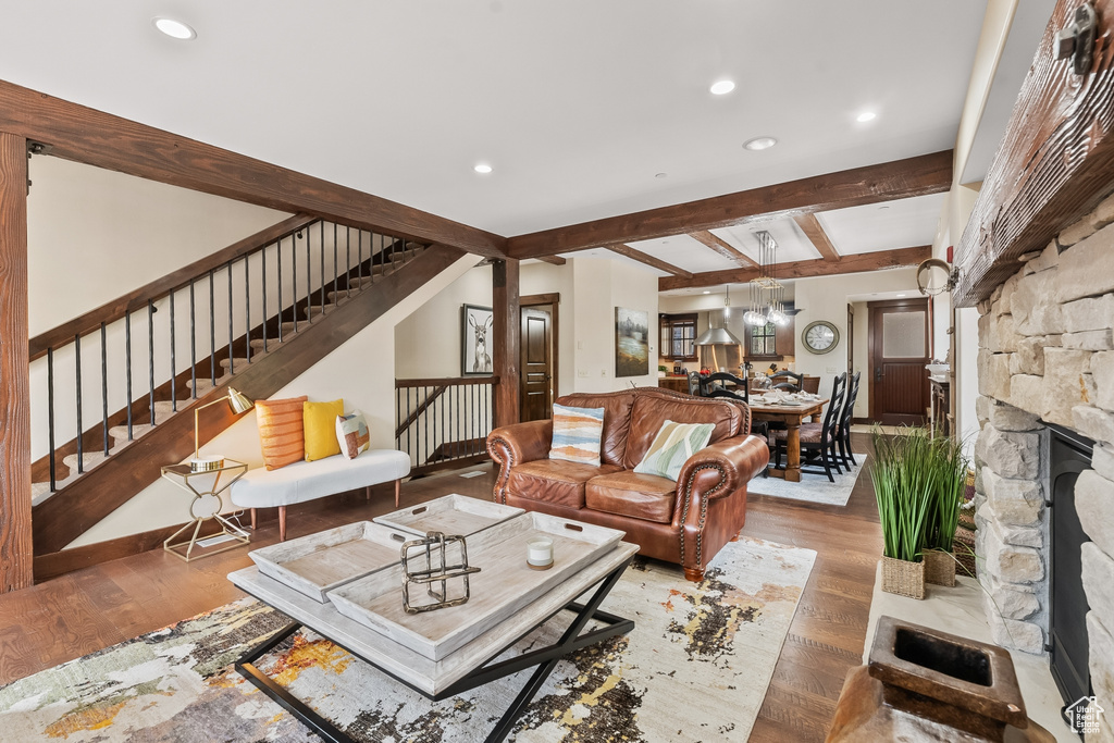 Living room featuring beamed ceiling, hardwood / wood-style floors, and a stone fireplace