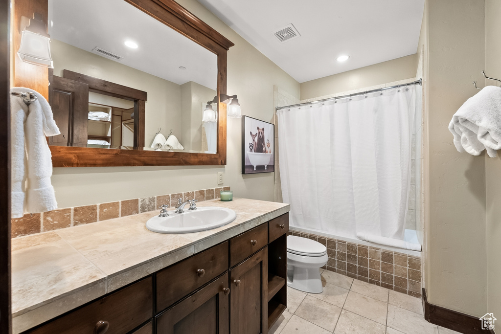 Full bathroom with shower / bath combo with shower curtain, vanity, toilet, and tile floors