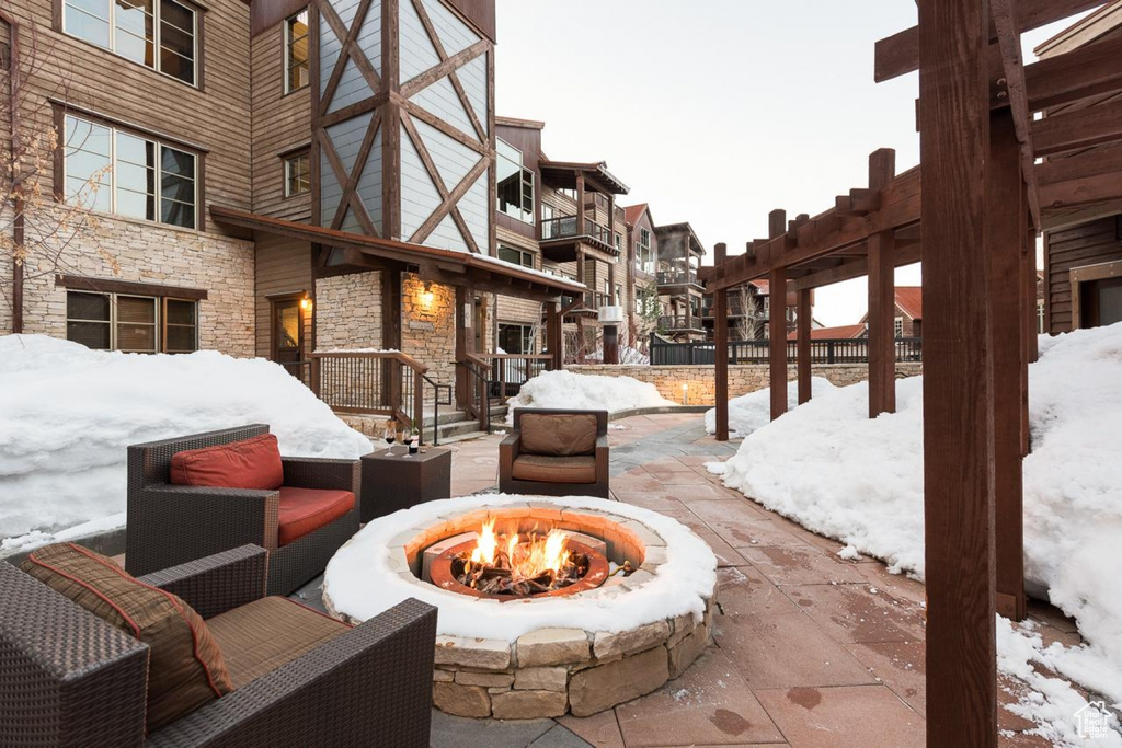 Snow covered patio with an outdoor living space with a fire pit