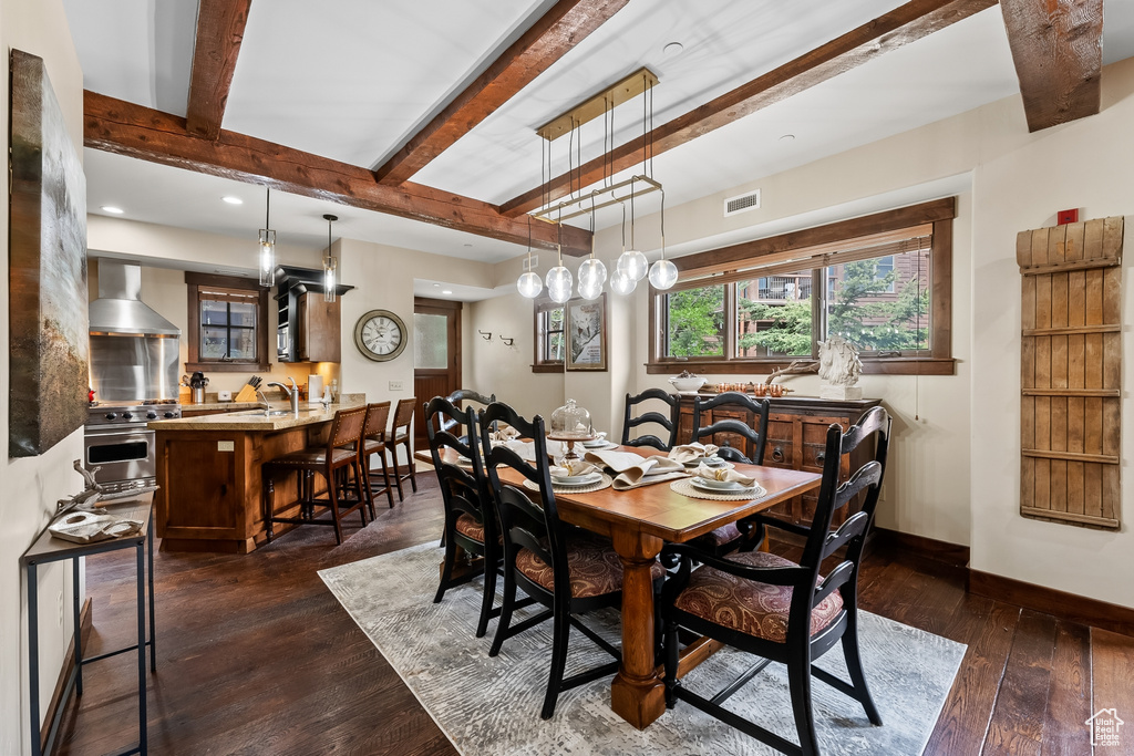 Dining area with dark hardwood / wood-style floors and beam ceiling