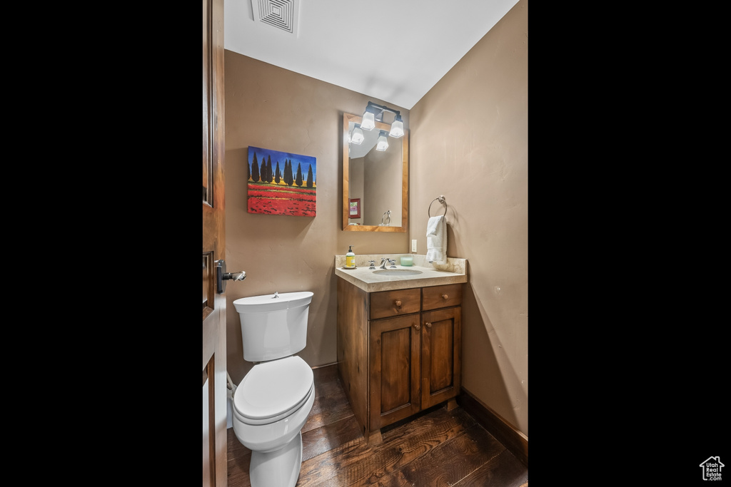 Bathroom featuring large vanity, toilet, and hardwood / wood-style floors