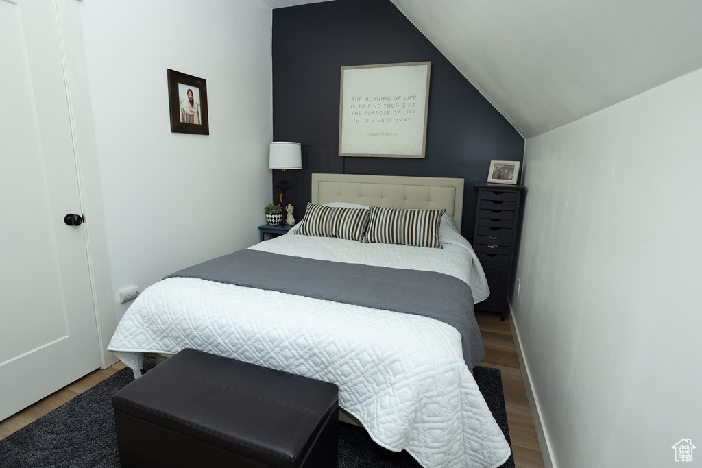 Bedroom with vaulted ceiling and dark wood-type flooring