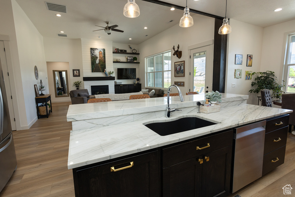 Kitchen with light hardwood / wood-style flooring, dishwasher, a center island with sink, sink, and pendant lighting