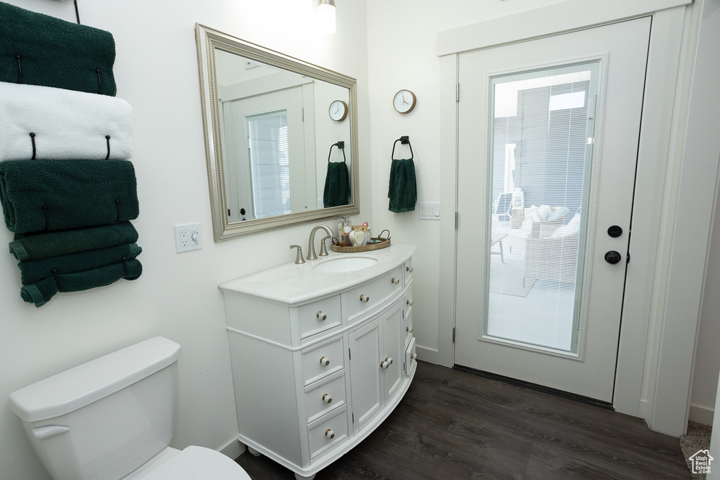 Bathroom with large vanity, toilet, and wood-type flooring