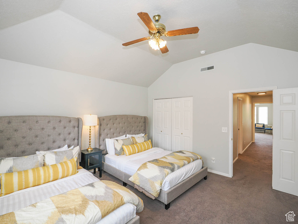 Bedroom with lofted ceiling, dark colored carpet, ceiling fan, and a closet