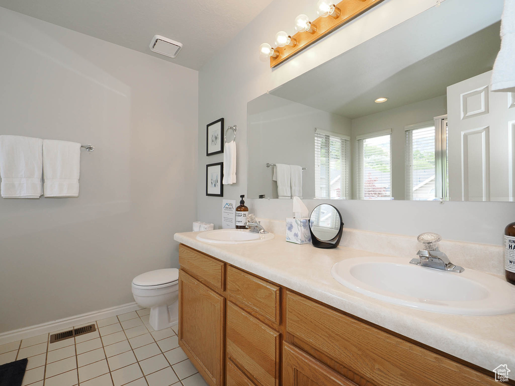 Bathroom with tile floors, double vanity, and toilet