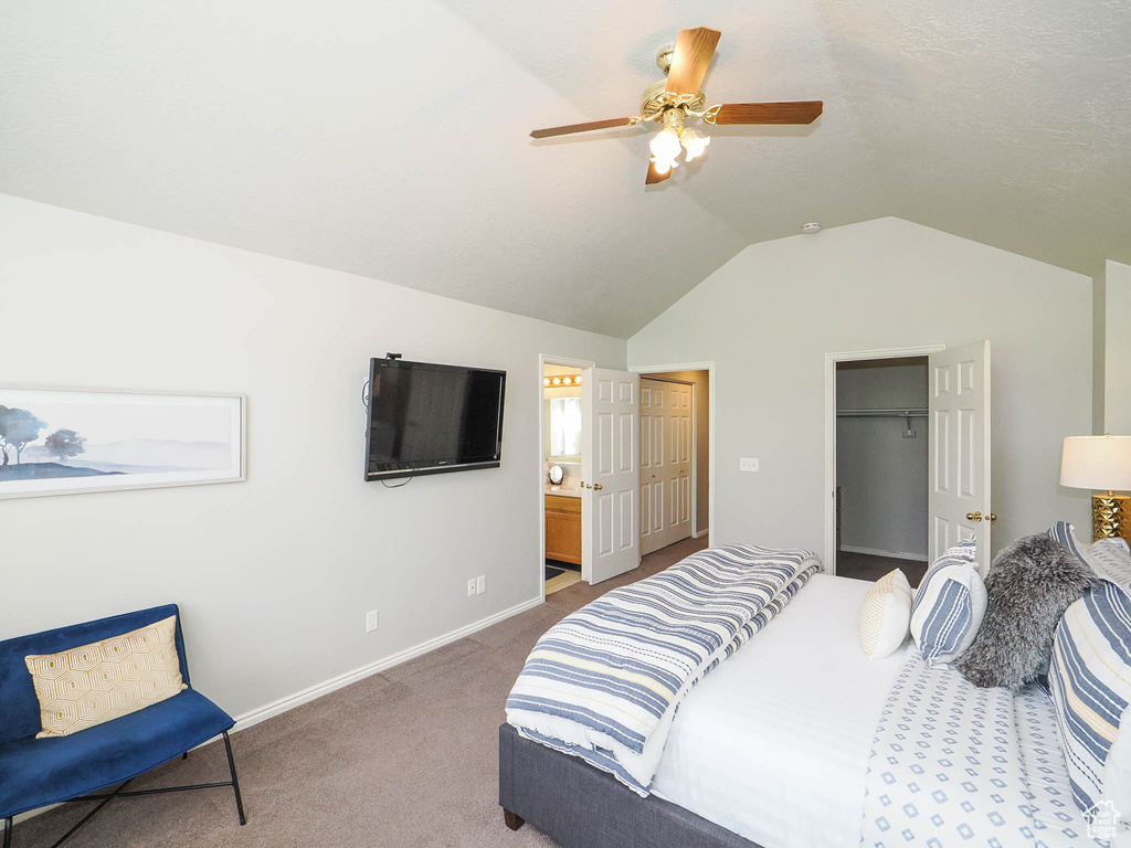 Bedroom featuring ceiling fan, a closet, vaulted ceiling, ensuite bath, and carpet