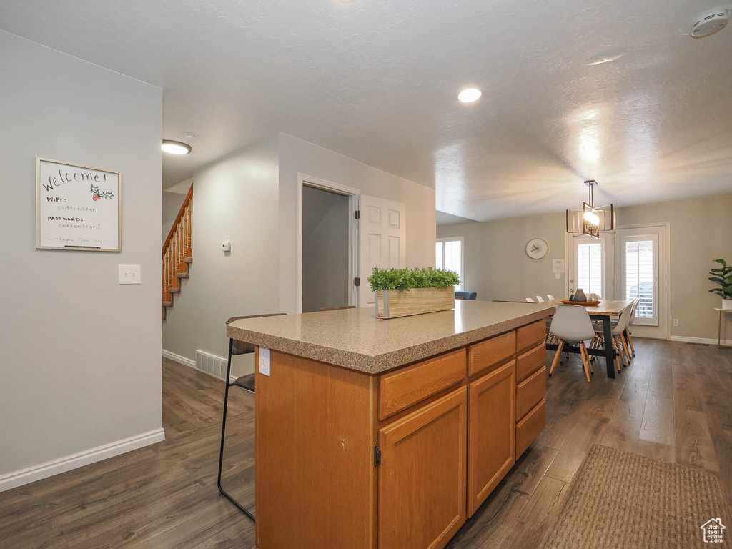 Kitchen featuring a notable chandelier, a center island, dark hardwood / wood-style floors, and pendant lighting