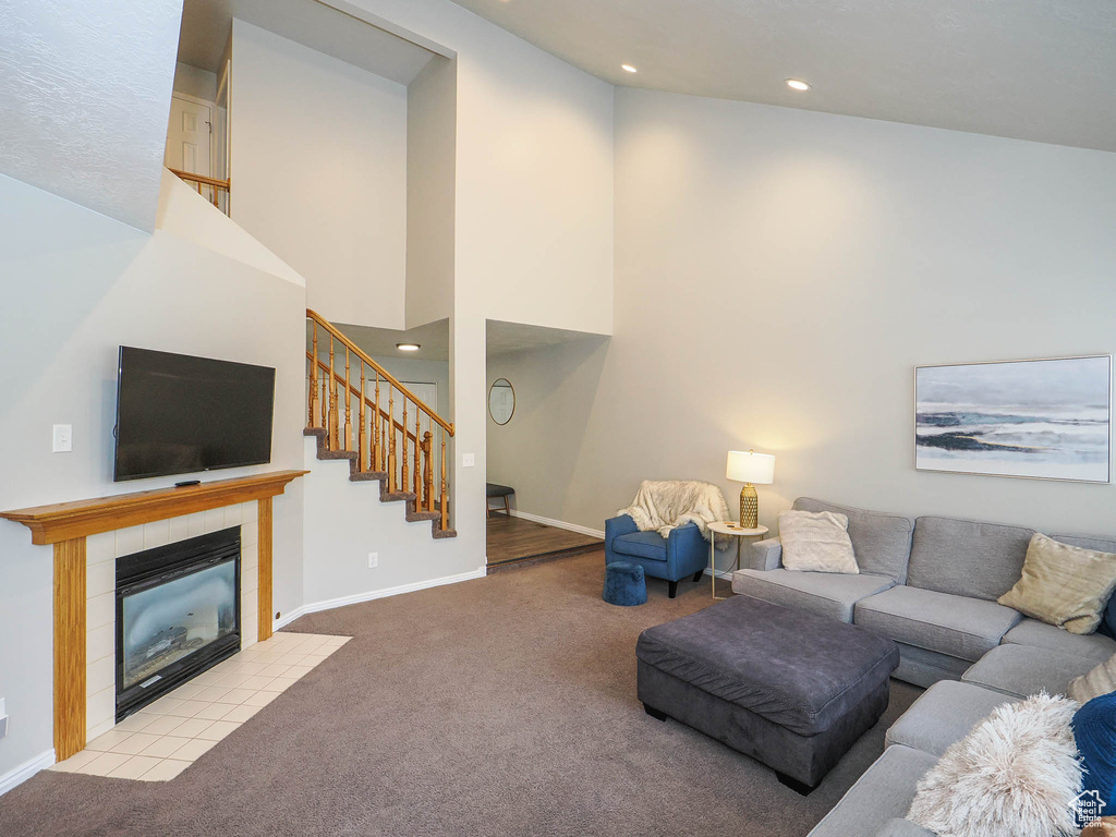 Living room featuring light carpet, a towering ceiling, and a tile fireplace