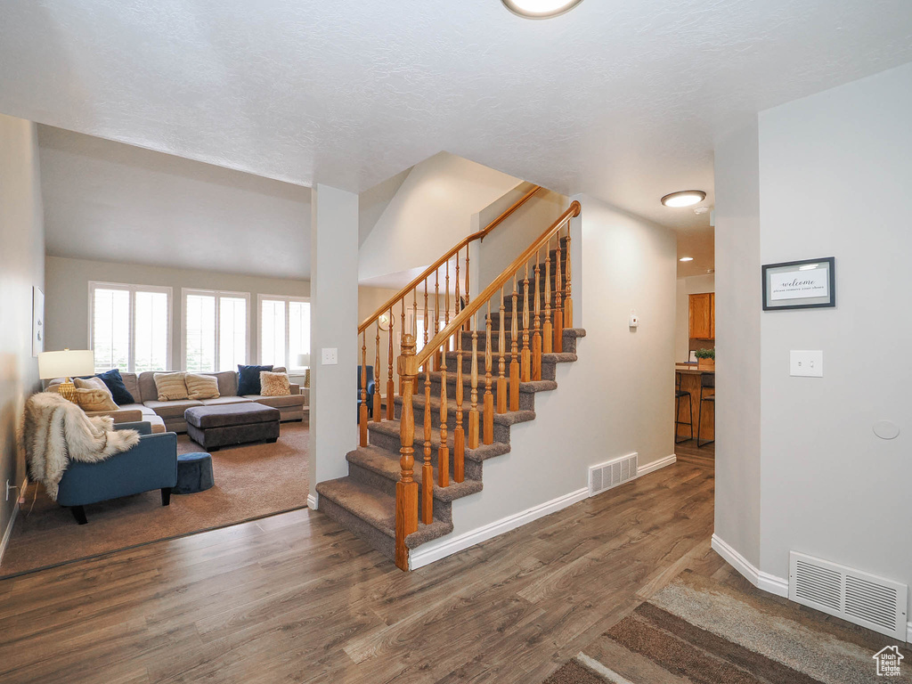 Stairs featuring a textured ceiling and dark carpet