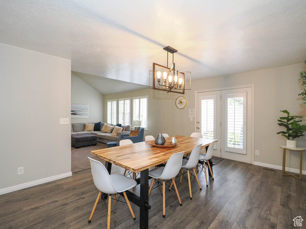 Dining area with a notable chandelier, lofted ceiling, and dark hardwood / wood-style flooring