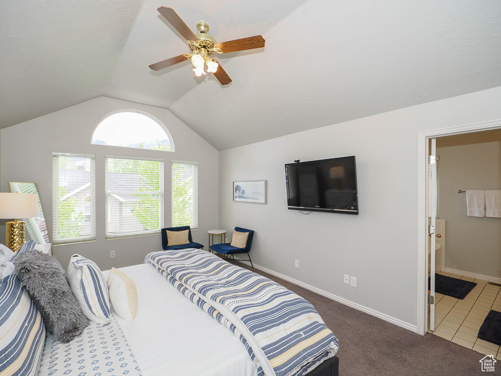 Bedroom with lofted ceiling, ceiling fan, dark tile floors, and ensuite bath