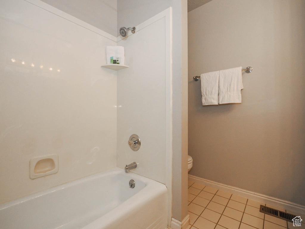 Bathroom with tile floors, toilet, and shower / bathing tub combination