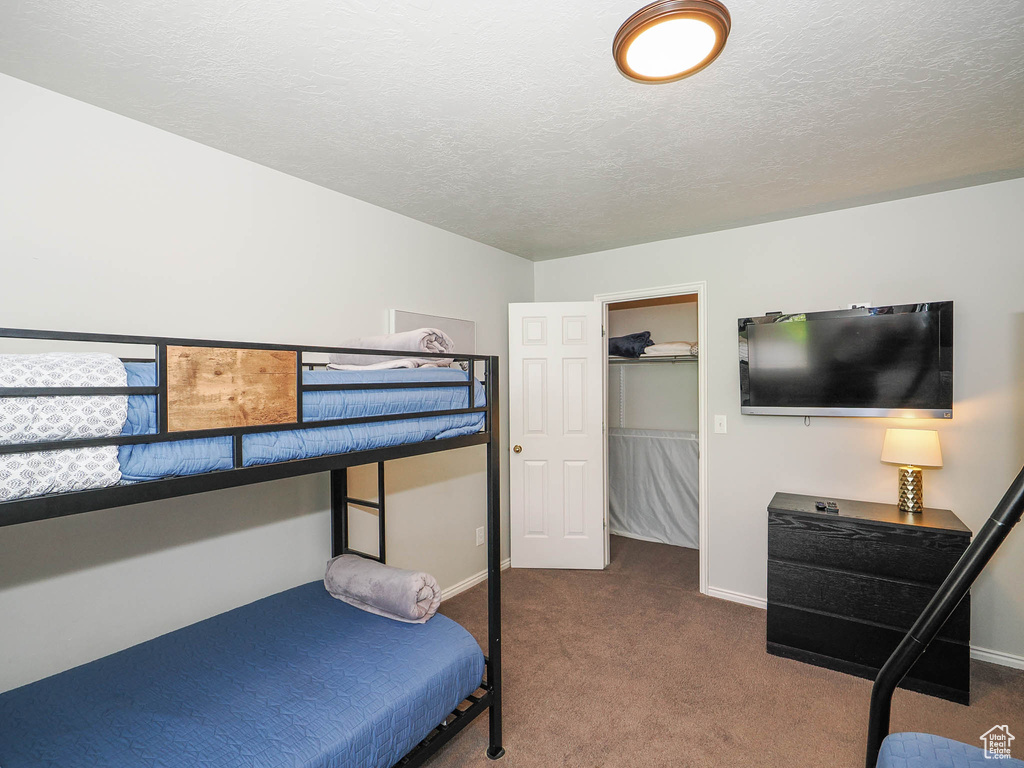 Carpeted bedroom featuring a walk in closet, a textured ceiling, and a closet