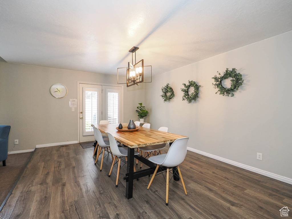 Dining area with a notable chandelier and dark wood-type flooring