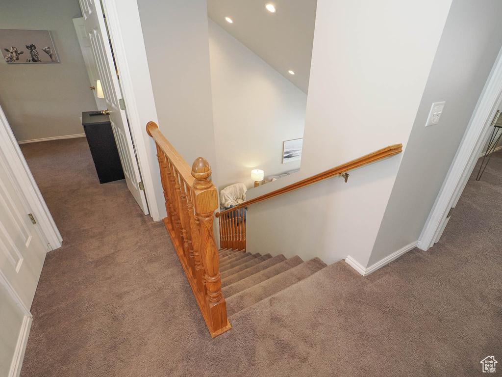 Stairway featuring vaulted ceiling and dark colored carpet