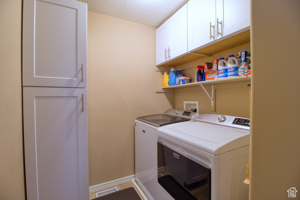 Laundry room featuring cabinets, a textured ceiling, independent washer and dryer, and hookup for a washing machine