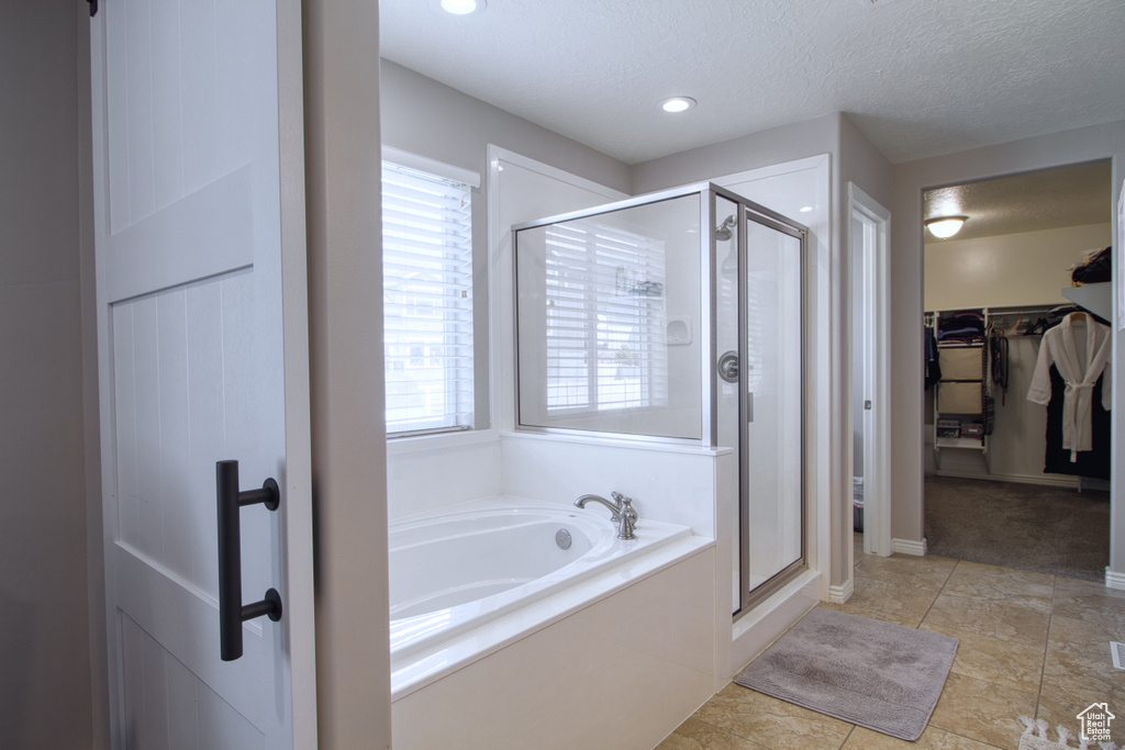 Bathroom featuring tile flooring, plenty of natural light, a textured ceiling, and plus walk in shower