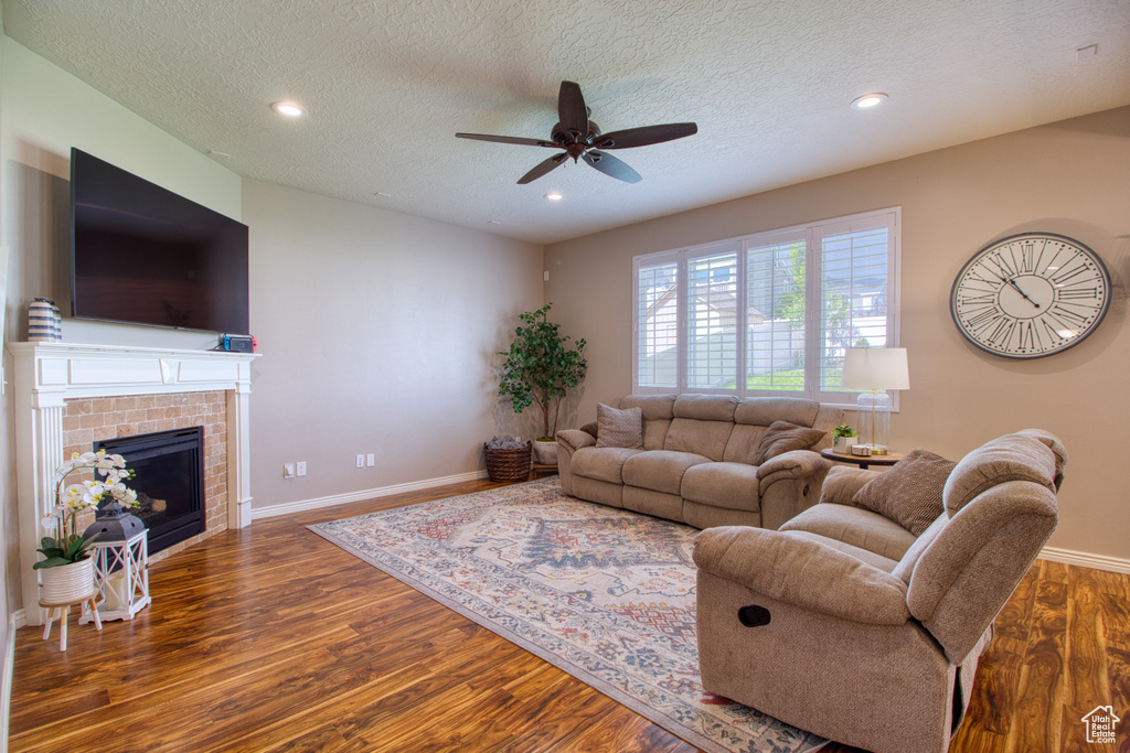 Living room featuring dark hardwood / wood-style floors, ceiling fan, a textured ceiling, and a fireplace