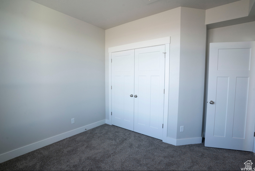 Unfurnished bedroom featuring a closet and dark carpet