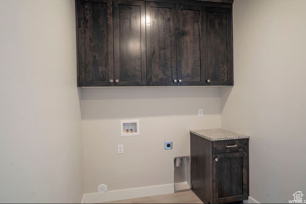 Clothes washing area with gas dryer hookup, light hardwood / wood-style flooring, washer hookup, electric dryer hookup, and cabinets