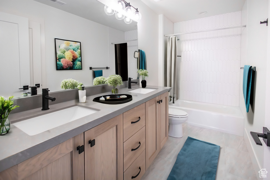 Full bathroom featuring bathing tub / shower combination, double sink vanity, tile flooring, and toilet